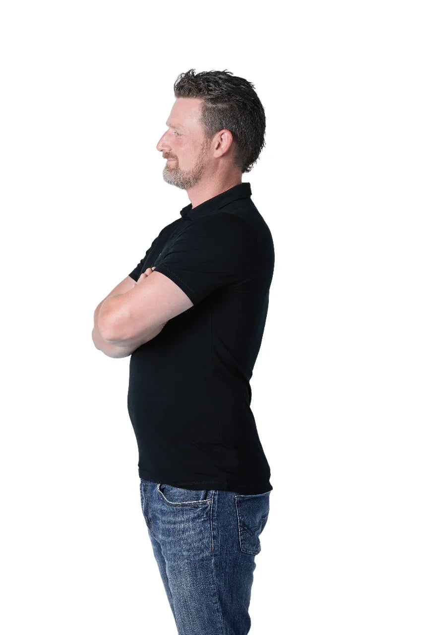 Man in black golf polo shirt and blue jeans, side view on white background