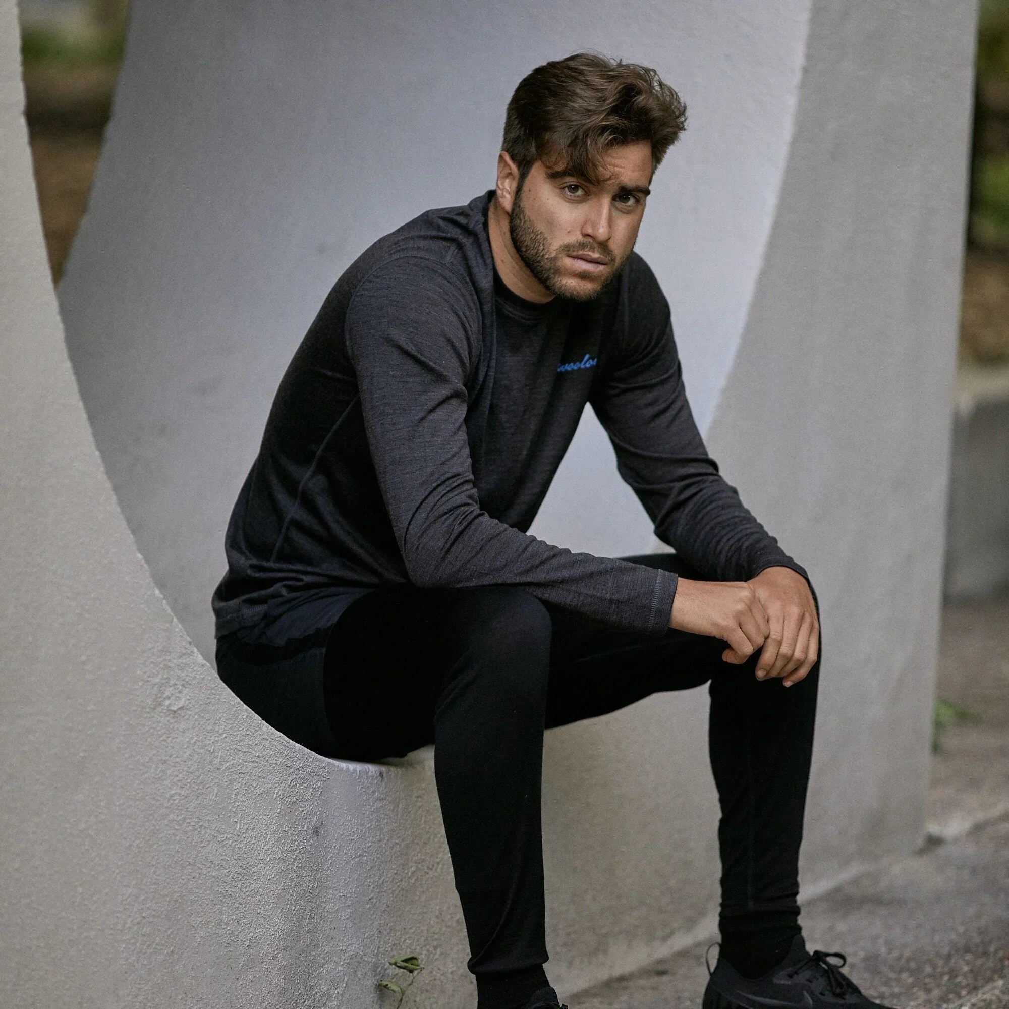 Man wearing black merino wool long sleeve crew neck shirt sitting outdoors