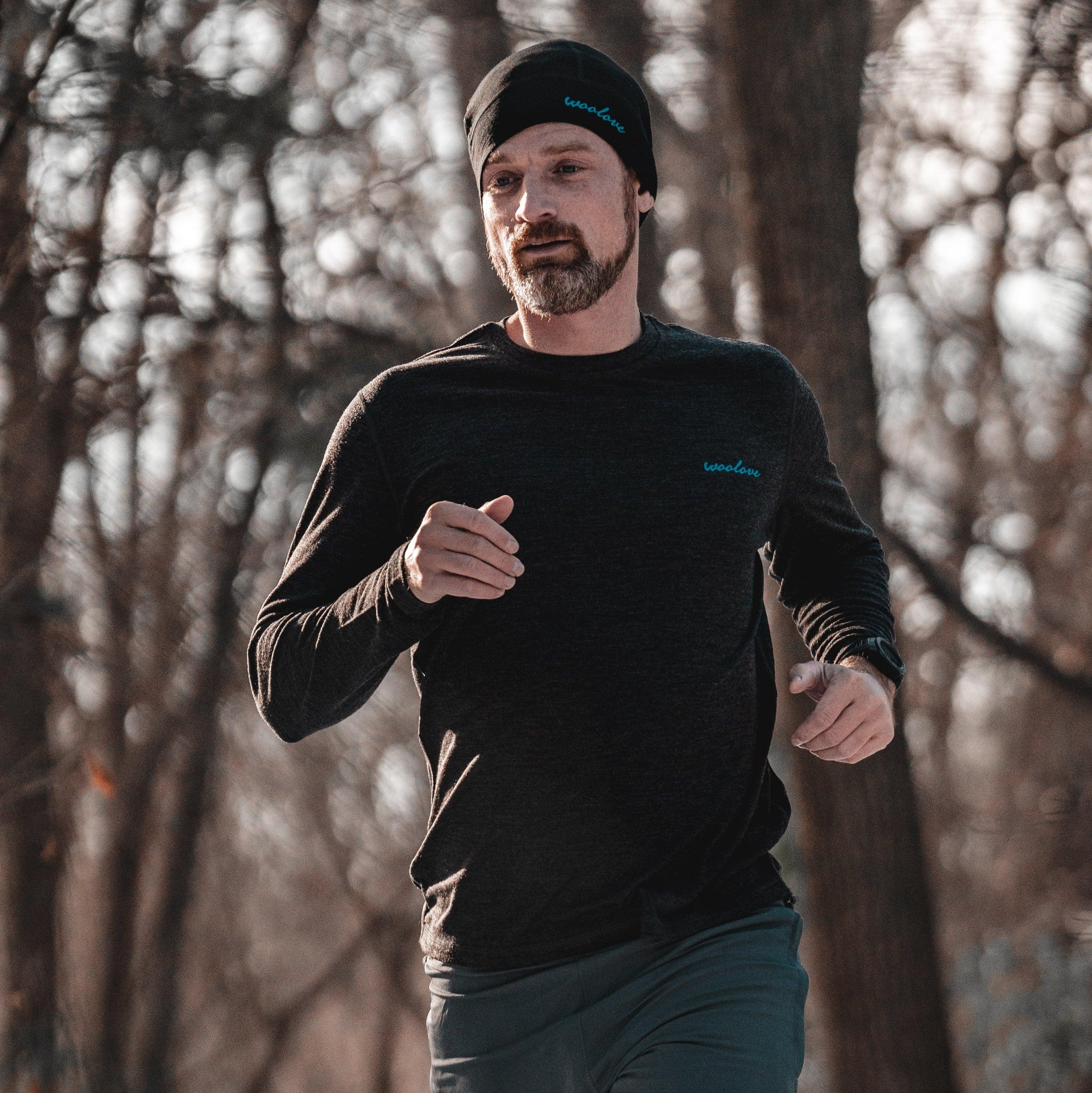 Man jogging outdoors in winter wearing black woolen shirt and beanie in forest setting