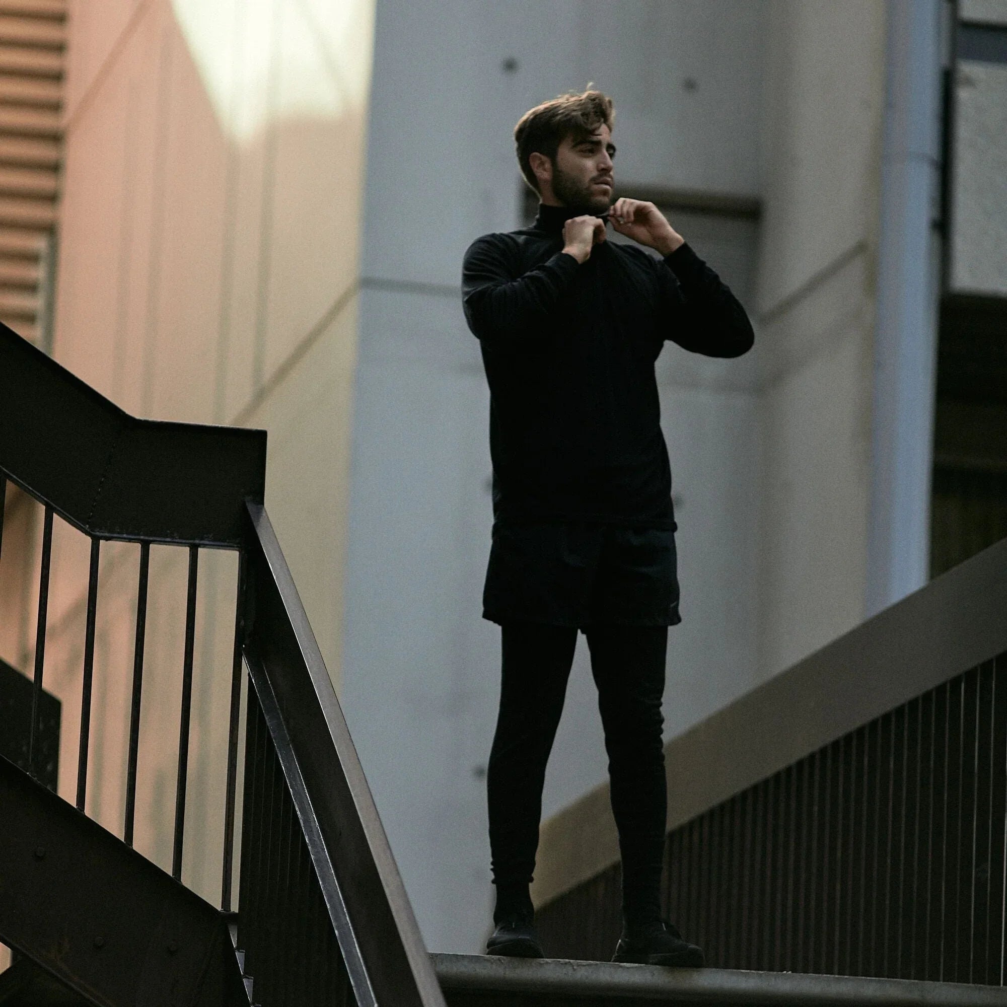 Man wearing black merino wool base layer leggings and top on urban staircase