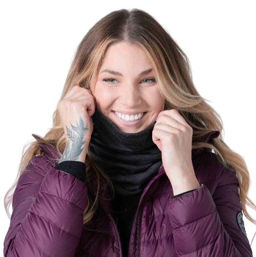 Smiling woman in a purple puffer jacket wearing a black neck gaiter on a white background