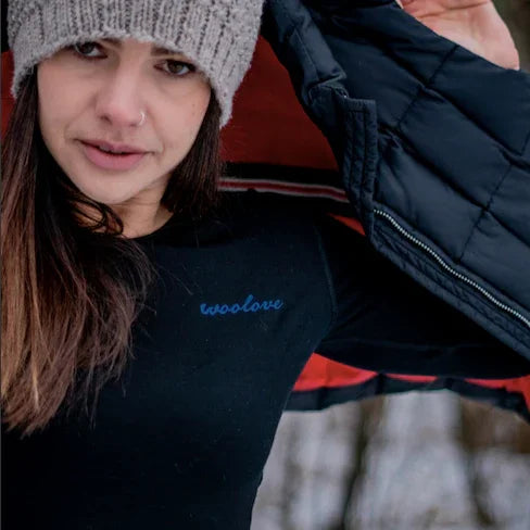 Woman in woollove thermal shirt, gray knit beanie, and black jacket outdoors in winter.