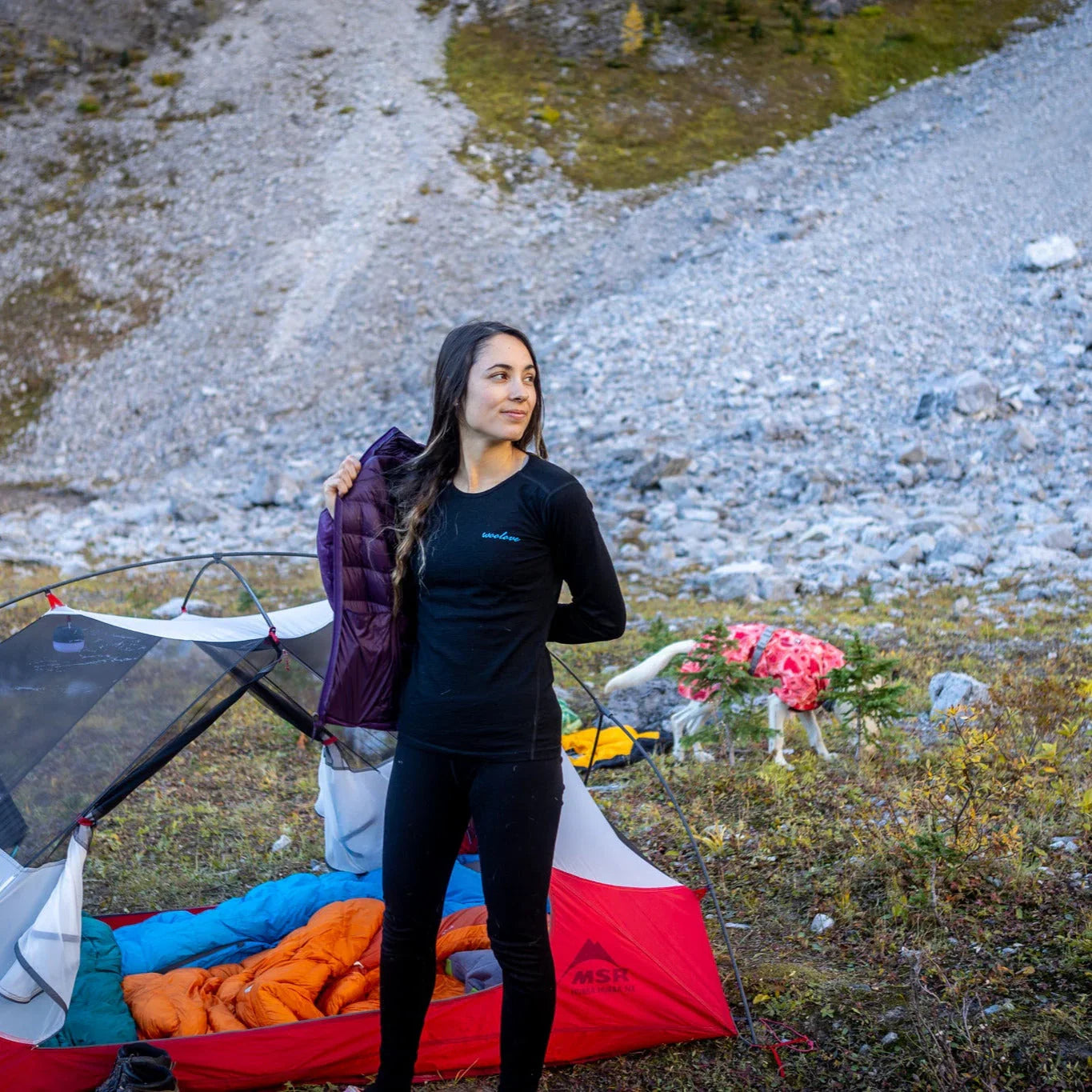 Woman in Woolove base layer by tent at mountain campsite with sleeping bags
