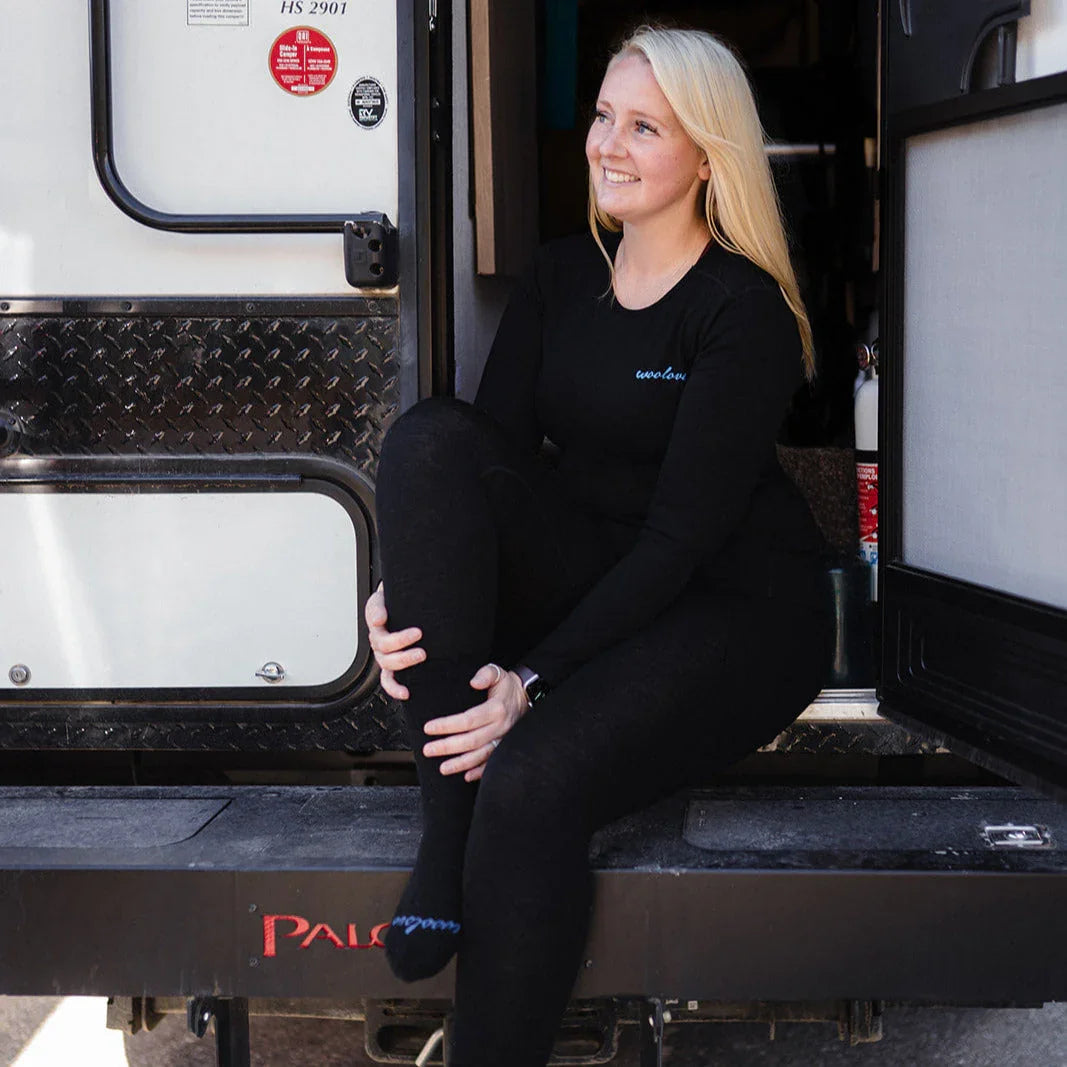 Woman in black thermal base layer sitting at RV entrance, outdoor adventure apparel