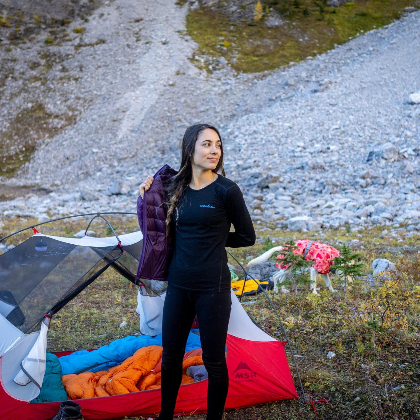 Woman in Woolove base layer at outdoor campsite beside tent in rocky mountain setting