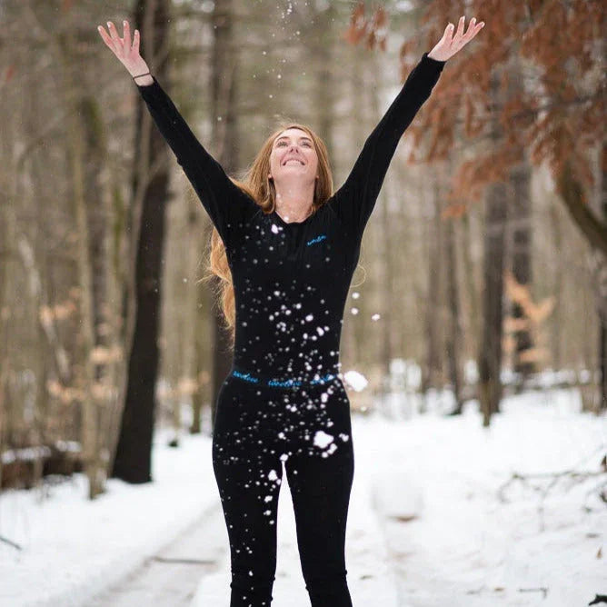 Woman in black thermal wear enjoying snow in a snowy forest winter scene