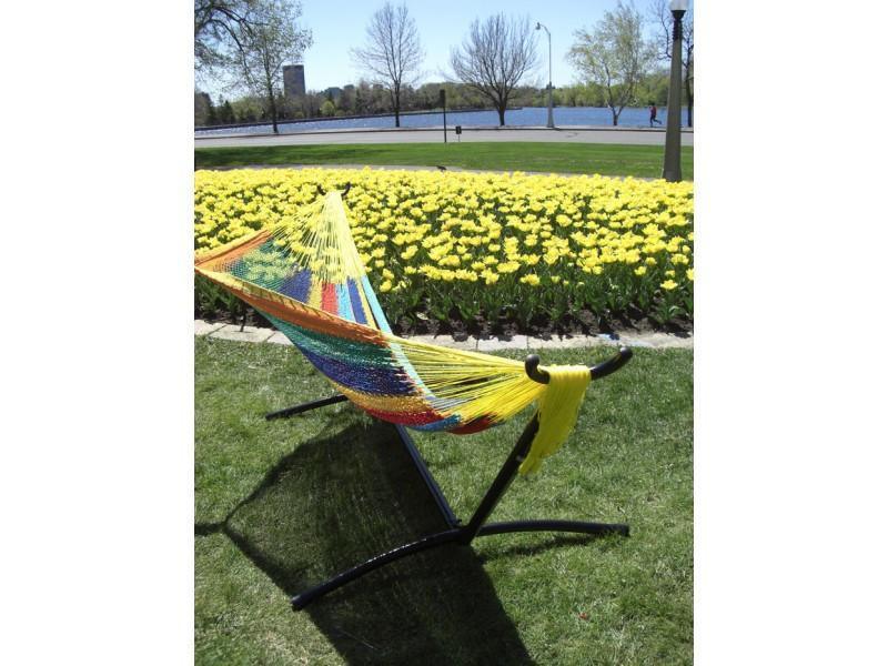 Colorful Mayan hammock on universal stand in garden with yellow flowers by a lake