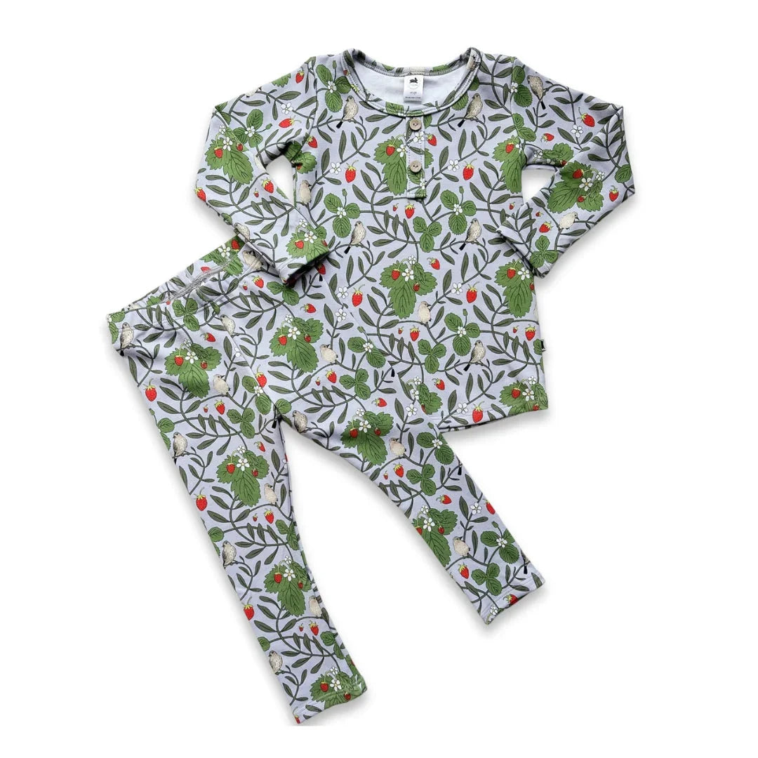 Children's pajama set with green leafy, bird, and red berry print on light gray fabric