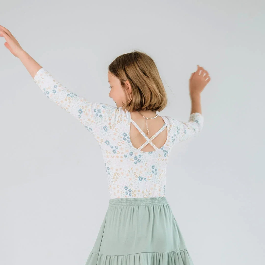 Girl wearing floral Audrey bodysuit with crisscross back and mint green skirt