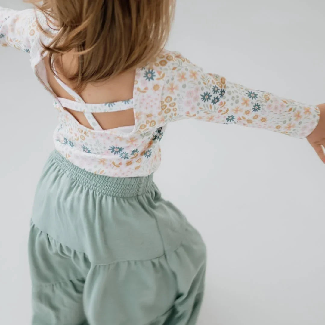 Girl wearing floral bamboo bodysuit and sage green skirt on white background