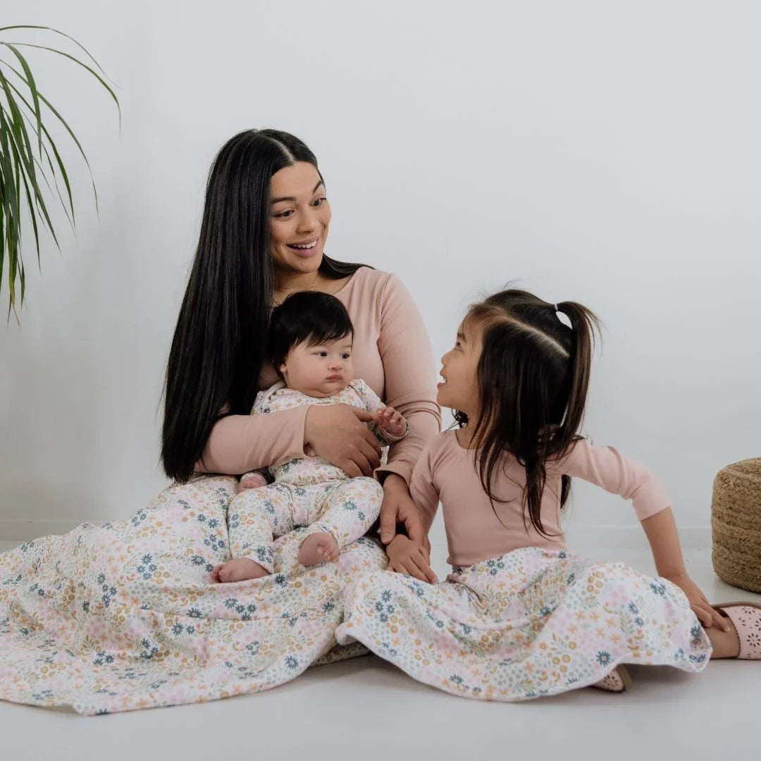 Mother and two children in matching pink floral bamboo Audrey bodysuits and blanket