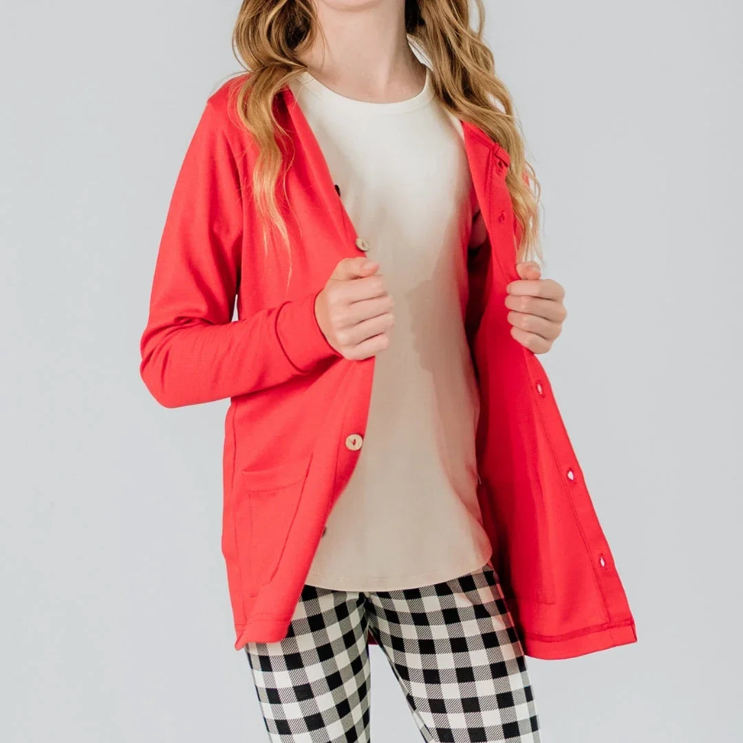 Youth girl wearing red cardigan with white shirt and checkered pants on gray background