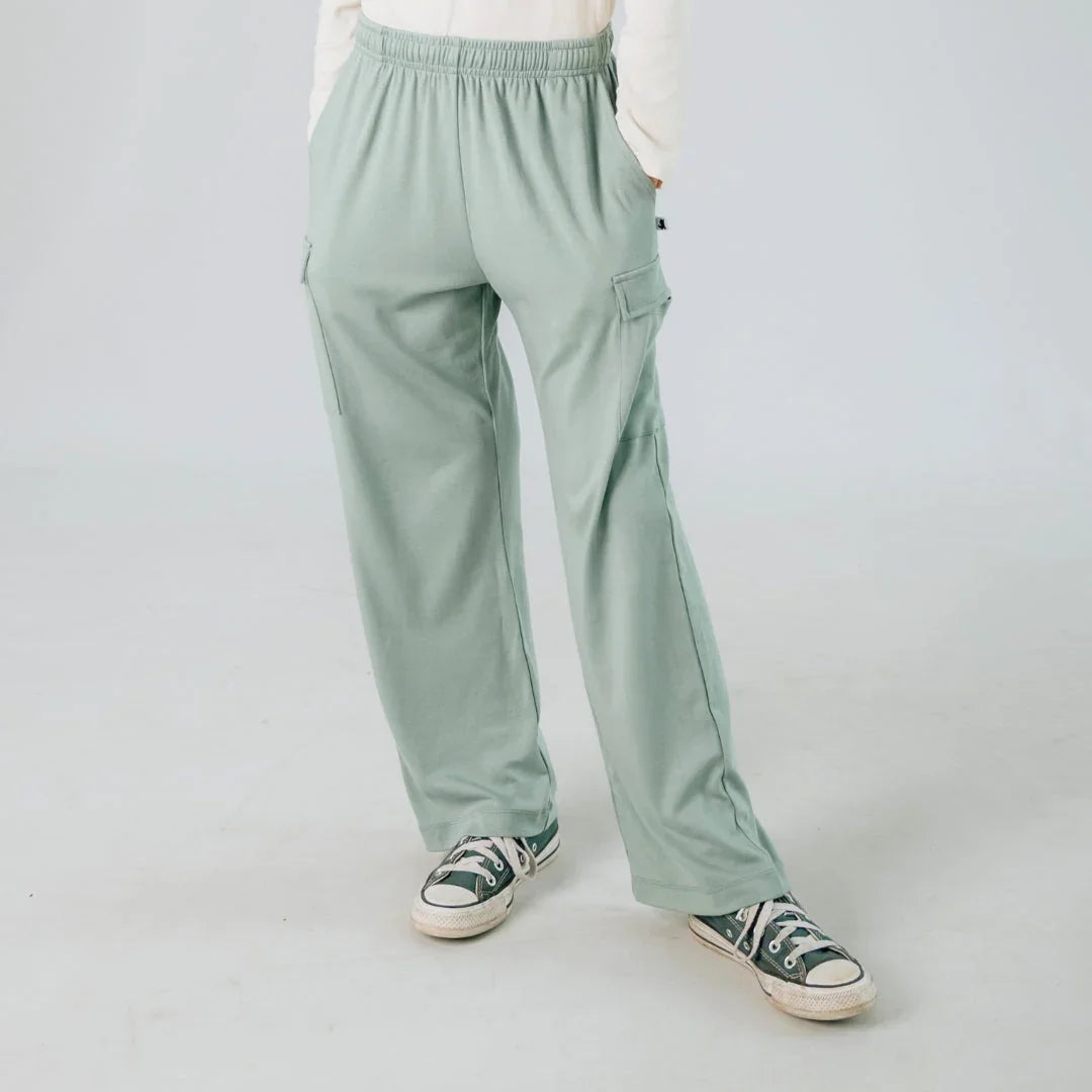 Youth sage green cargo pants with side pockets and elastic waist, worn with sneakers