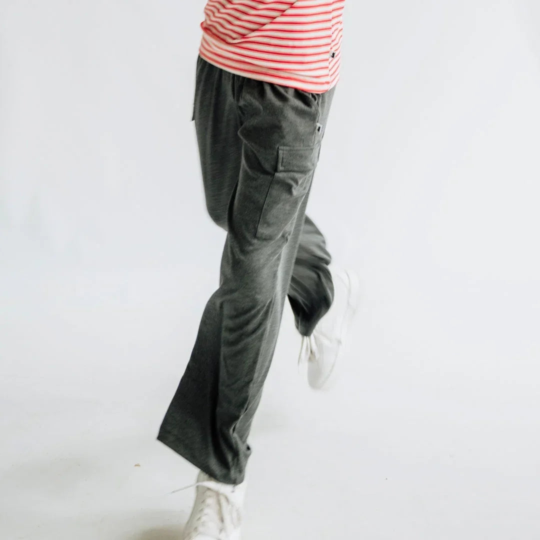 Person in grey jogger pants and white sneakers, red striped shirt, walking indoors