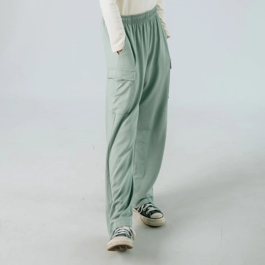 Loose mint green cargo pants with pockets, worn with black sneakers in a studio setting.