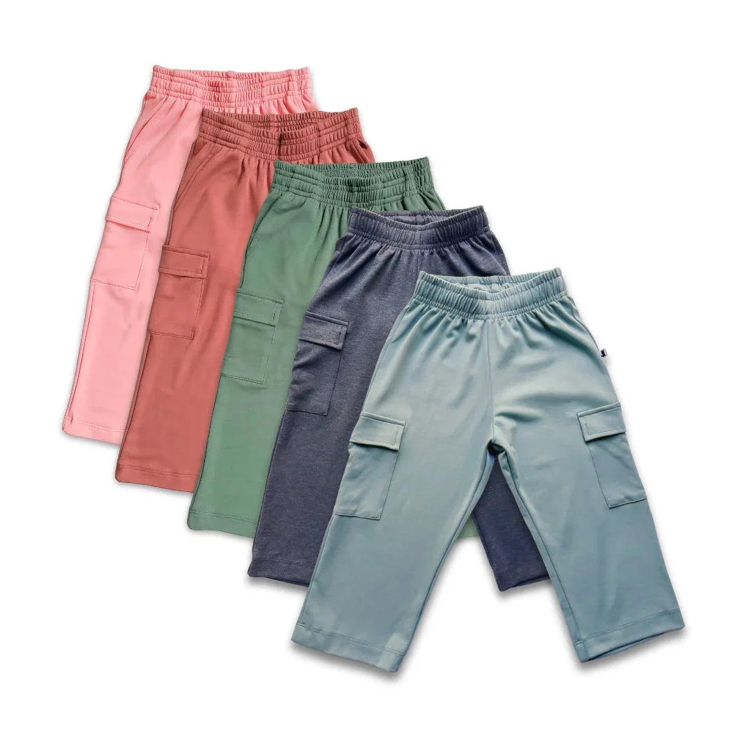 Assorted kids cargo pants in pastel colors with side pockets on white background