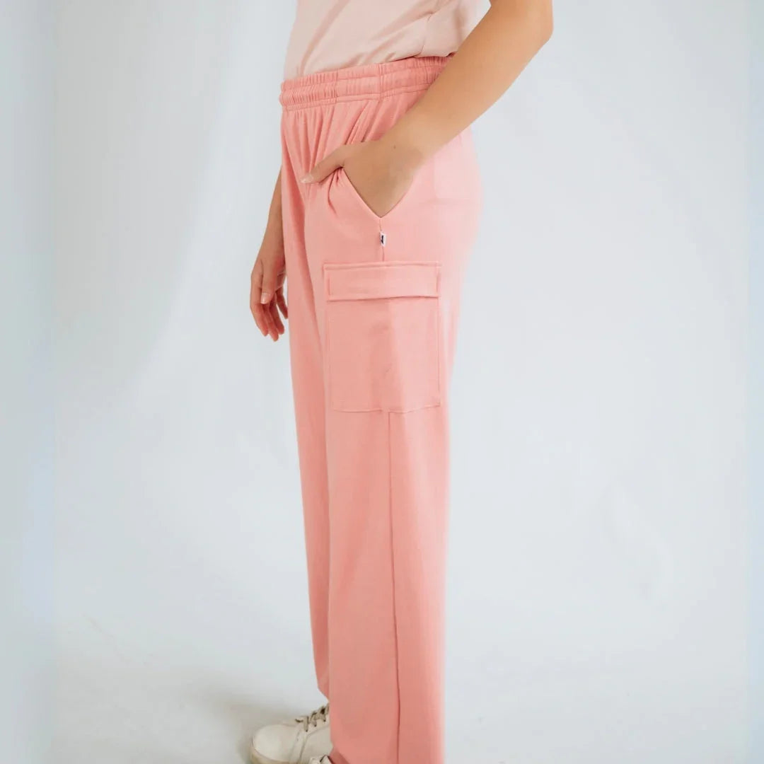 Youth wearing pink cargo pants with side pocket, white shoes, and a light background