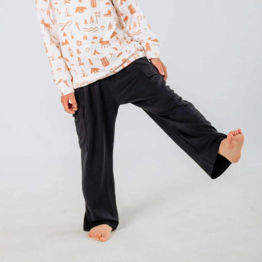 Kid wearing black cargo pants and patterned long sleeve shirt in studio
