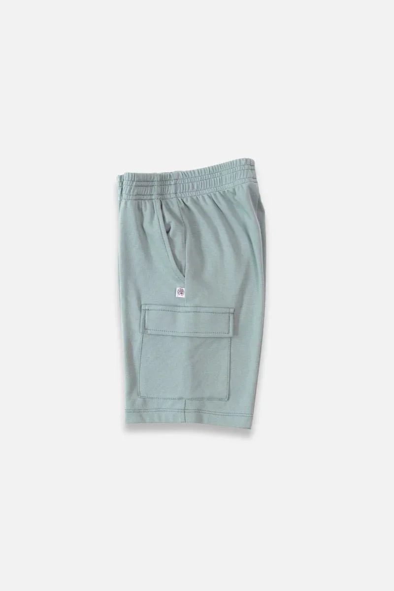 Light green athletic shorts with elastic waistband and large front pocket on plain background