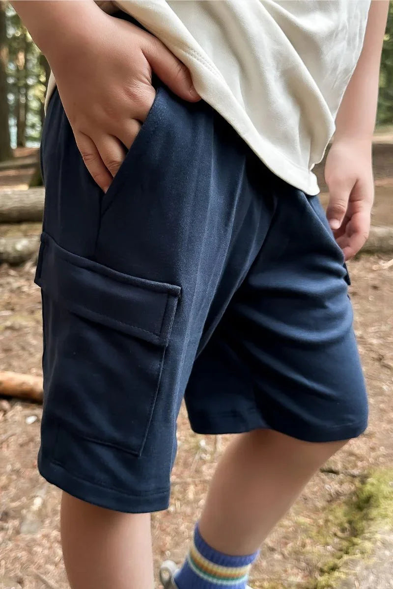 Youth wearing navy bamboo cargo shorts outdoors with hand in pocket