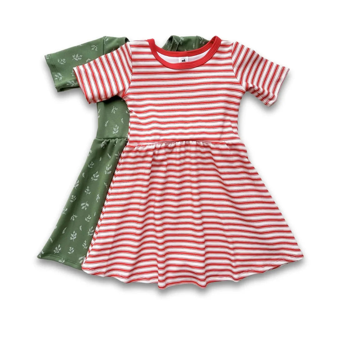 Two girls' dresses, one red striped and one green with white floral print, laid flat