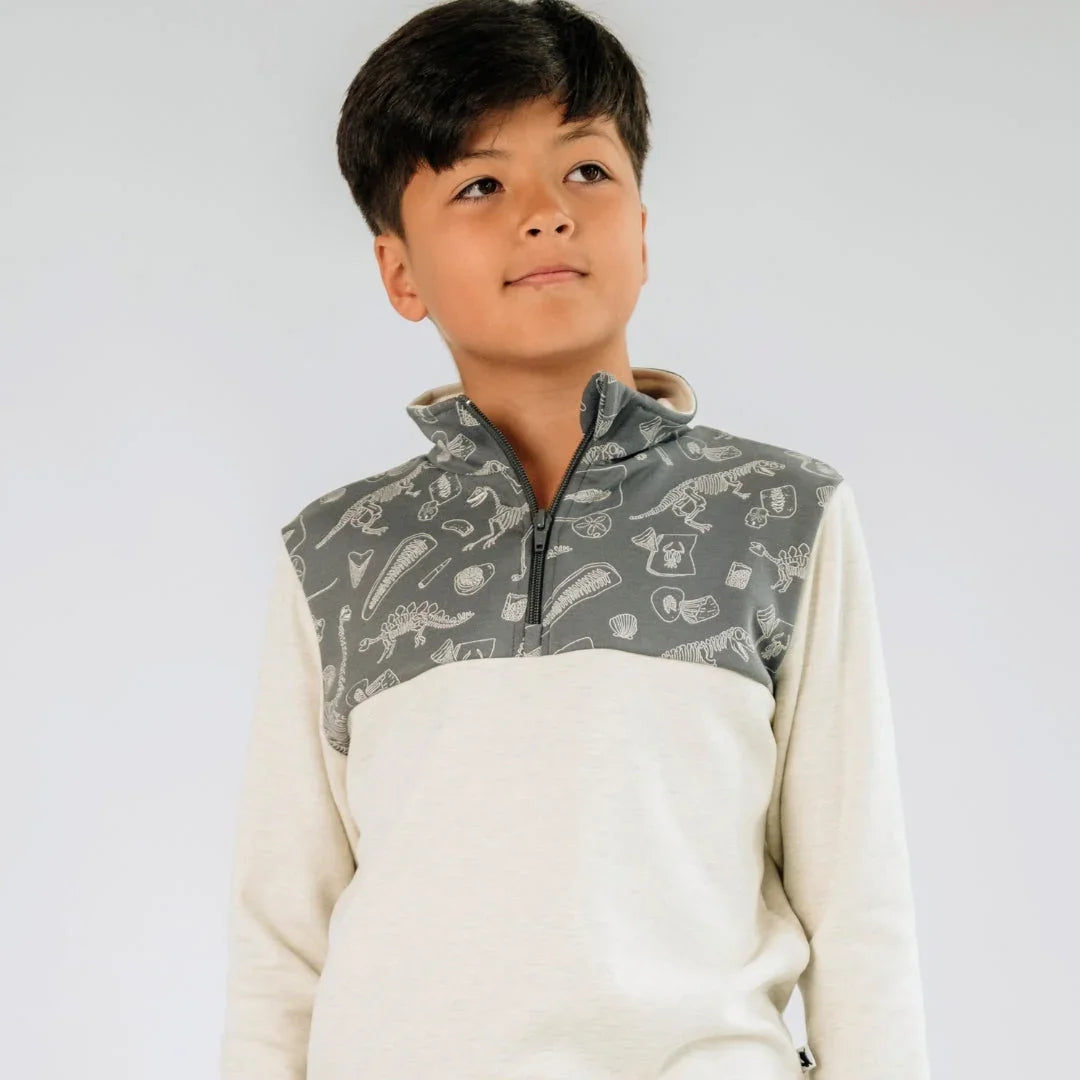 Boy wearing light cream youth half zip pullover with gray dinosaur print top panel