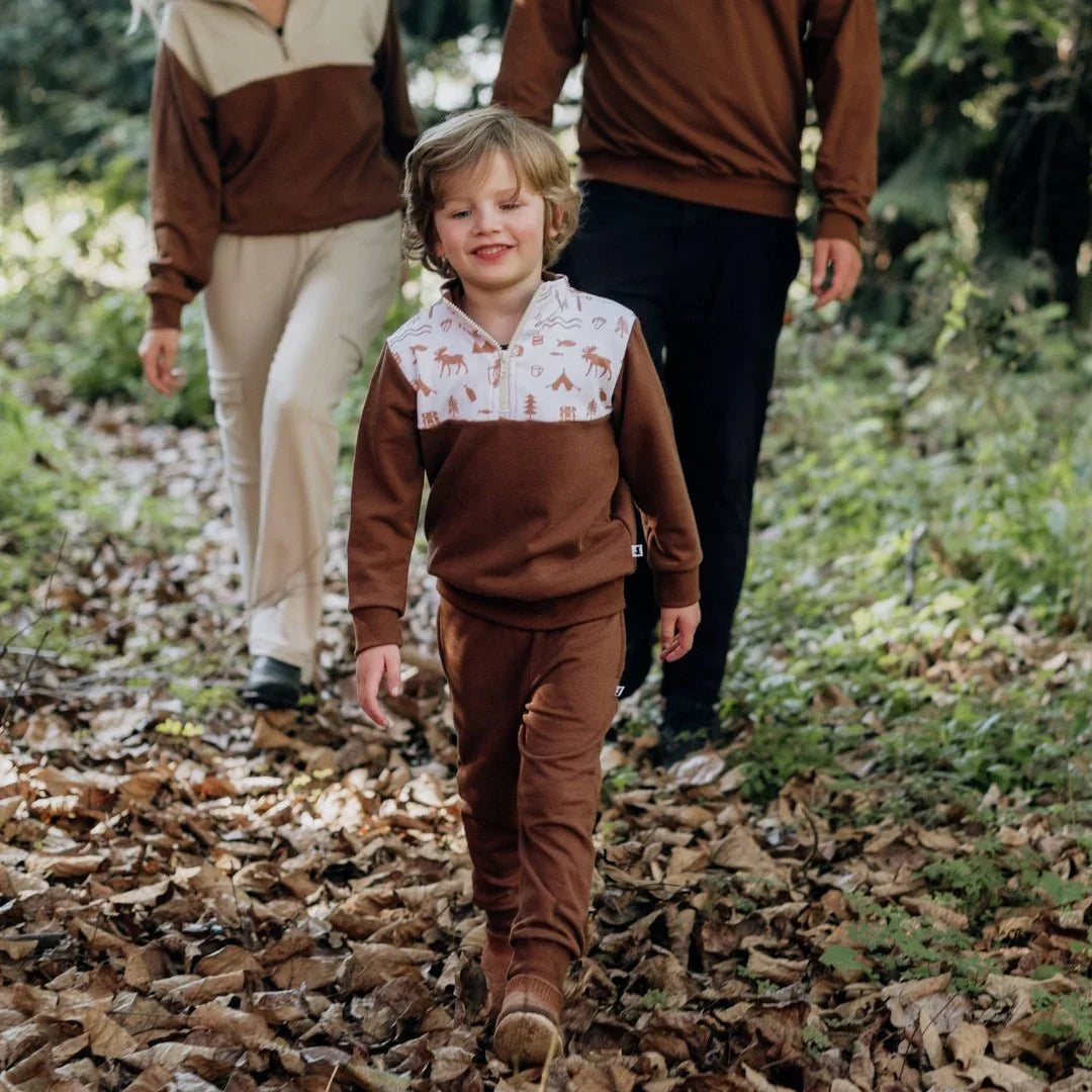 Child wearing bamboo fleece half-zip brown sweatshirt and pants walking outdoors in forest