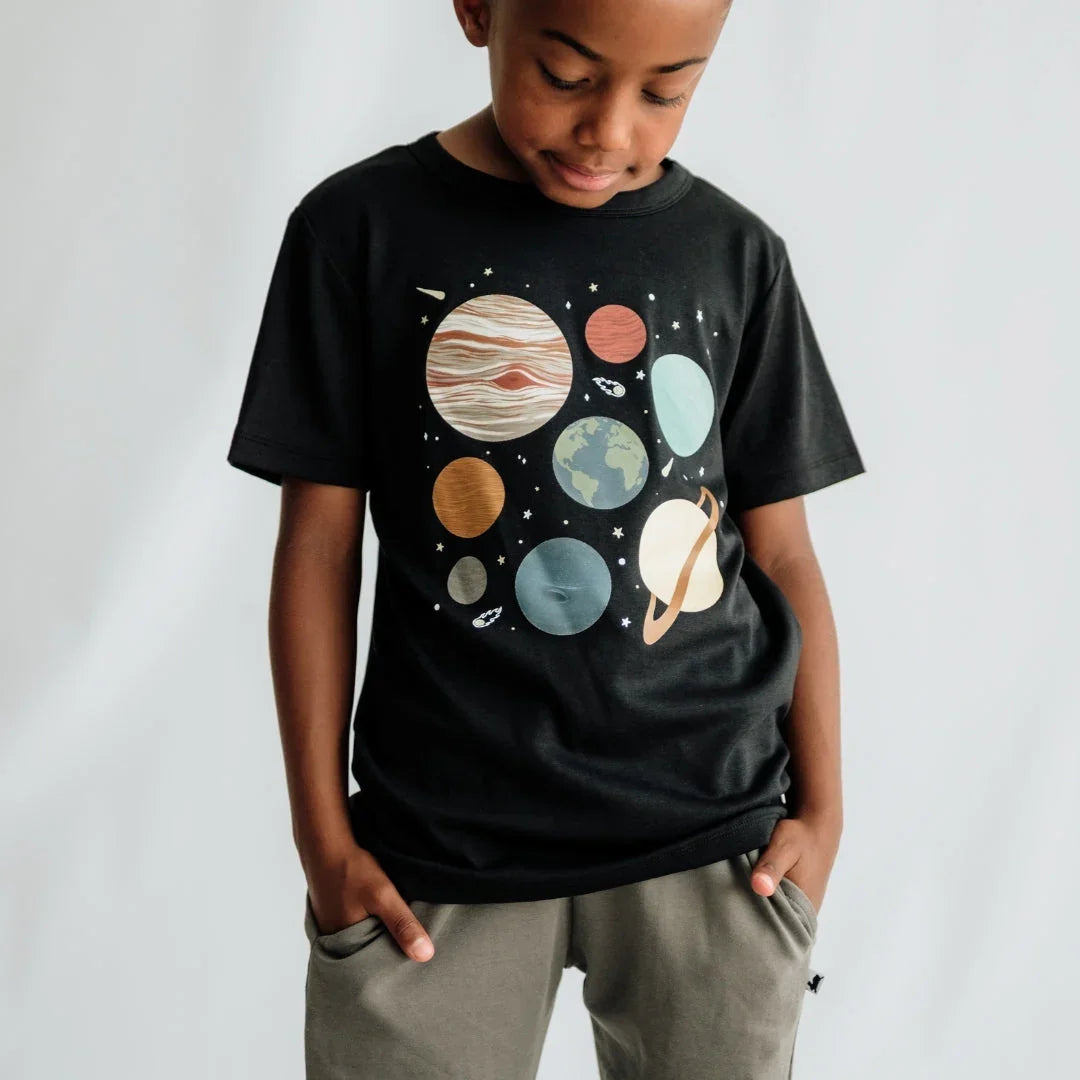 Boy wearing black t-shirt with solar system planets graphic, casual grey pants