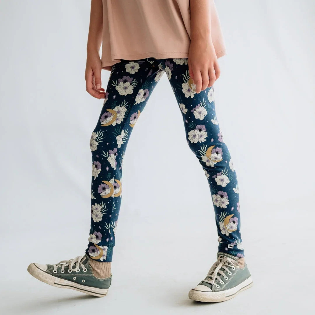 Girl wearing floral print leggings, pink top, and green sneakers on white background