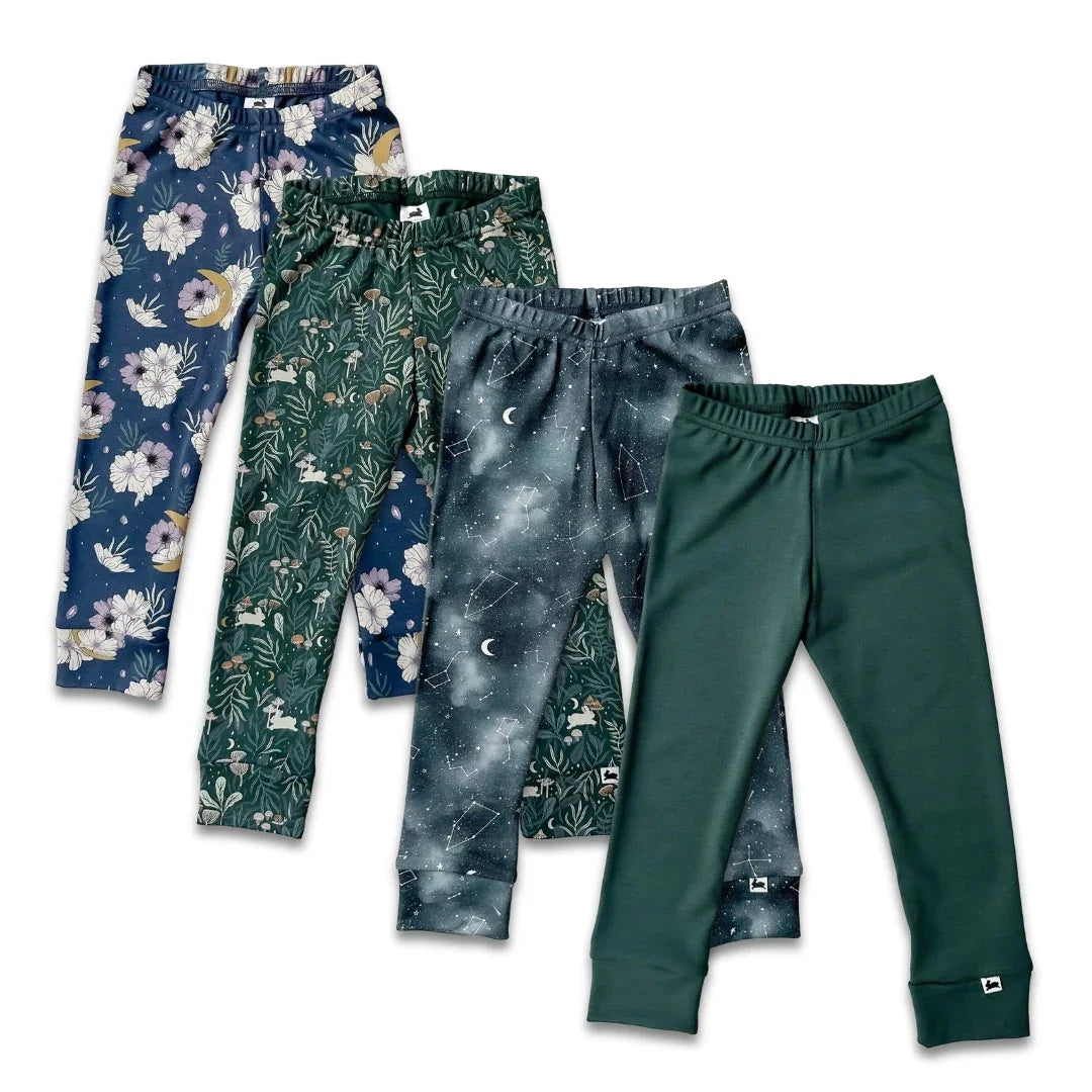 Four pairs of kids' leggings with floral, botanical, galaxy, and solid green patterns on white background