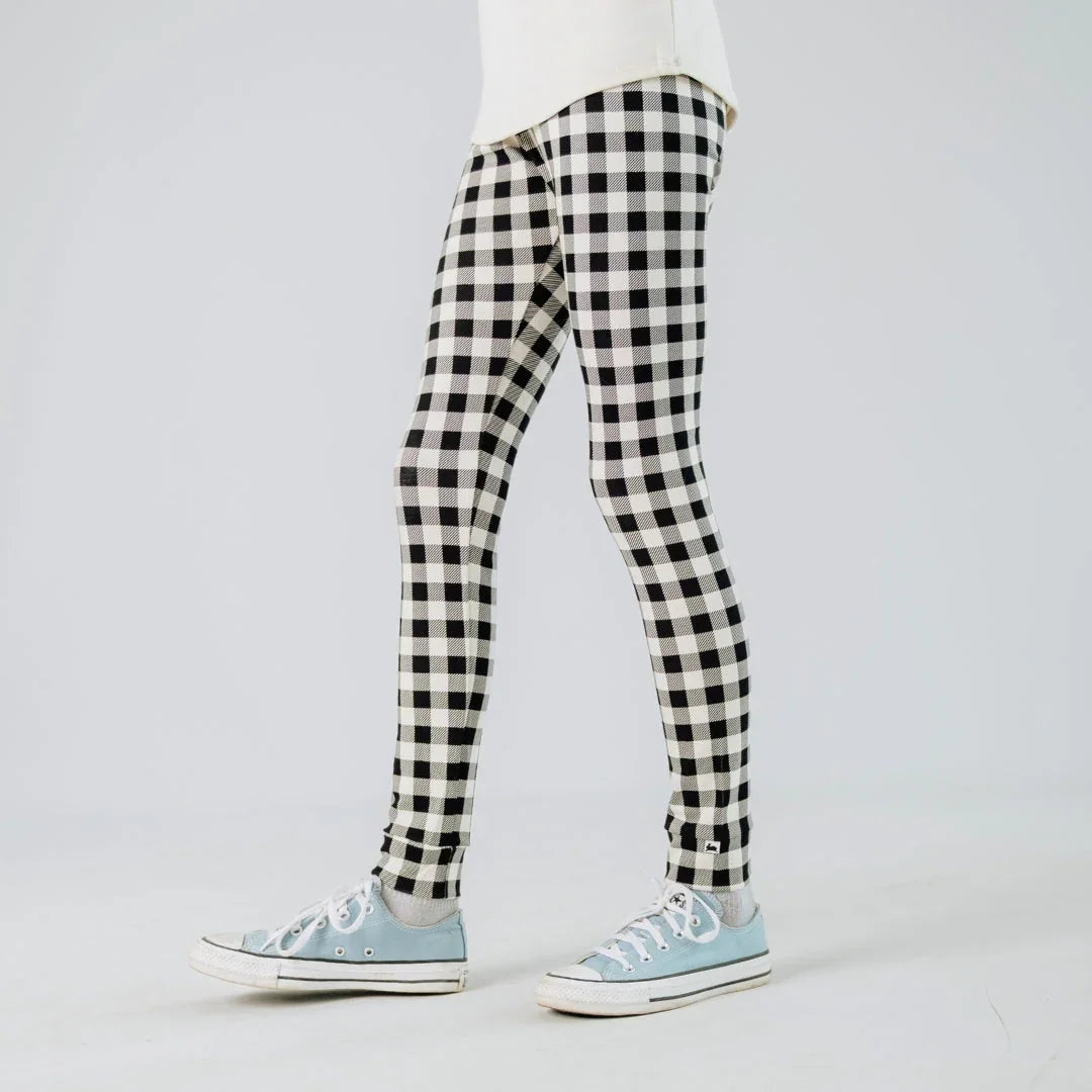 Black and white checkered leggings with light blue sneakers on a plain background