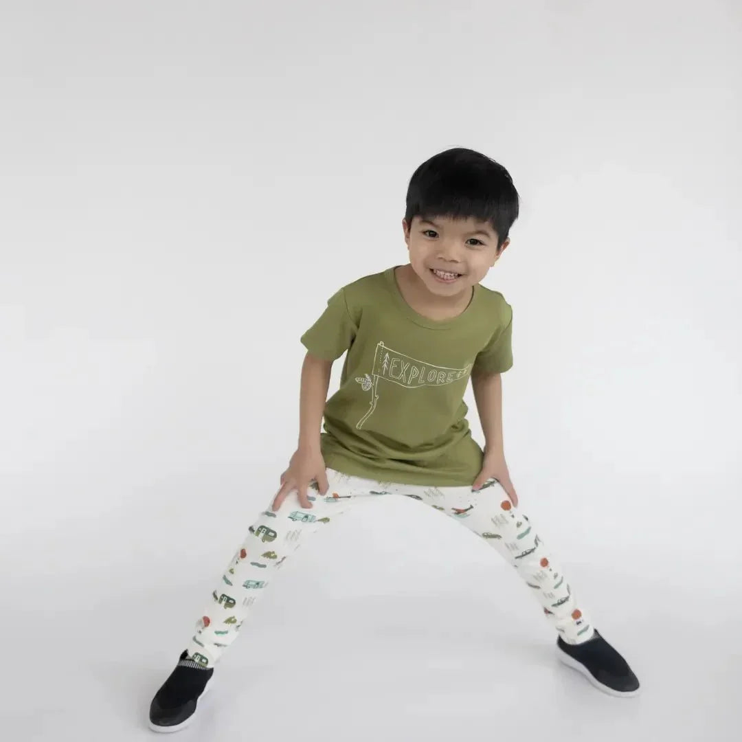 Smiling child wearing olive green explorer t-shirt and printed bamboo leggings