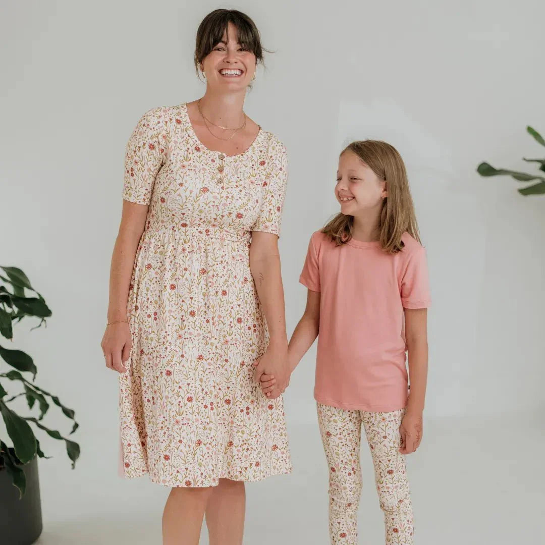 Woman in floral dress and girl in pink shirt with floral bamboo leggings, white background