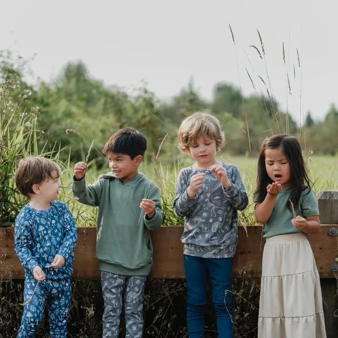 Kids wearing bamboo leggings and printed tops outdoors in a grassy field