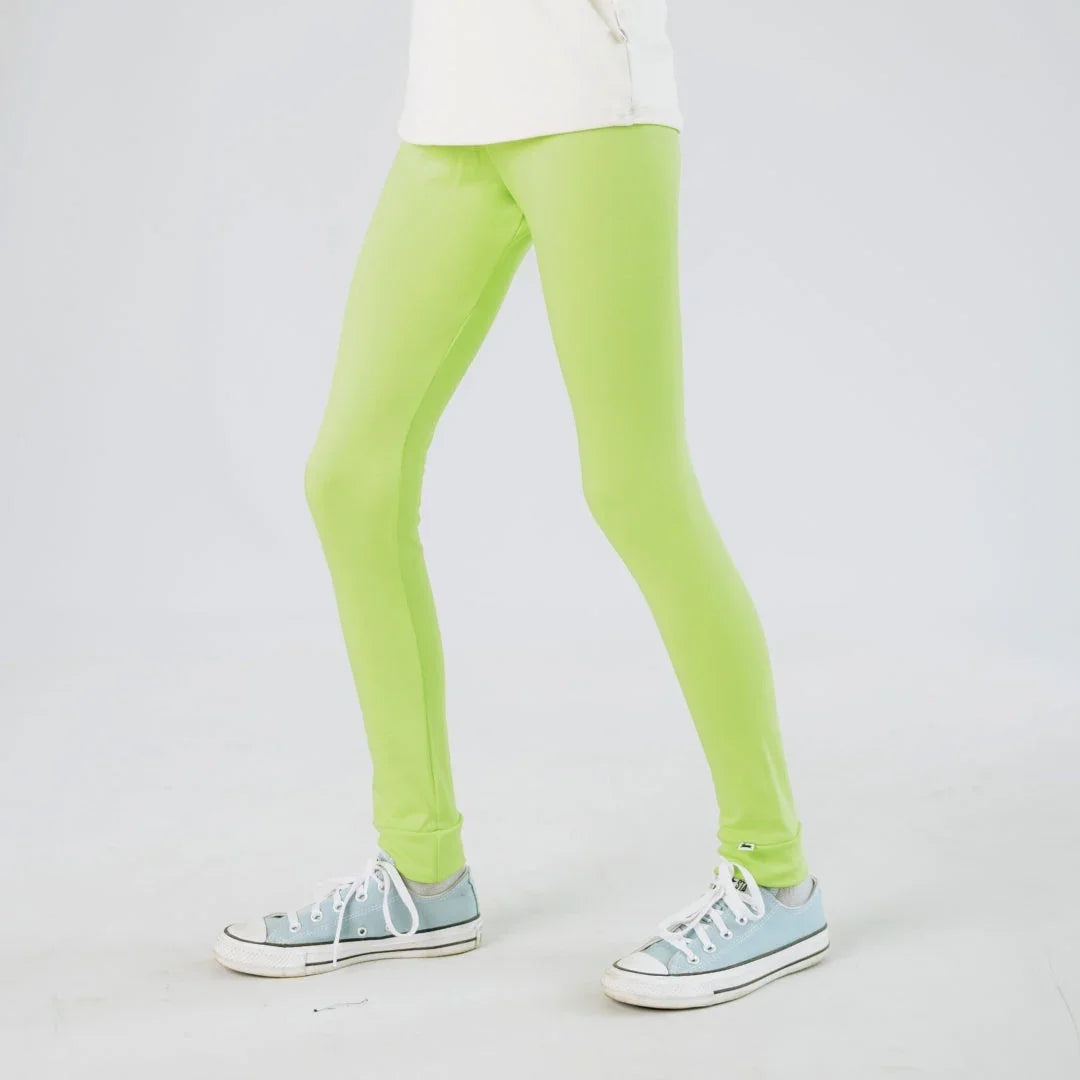 Child wearing neon green leggings and blue sneakers on a white background