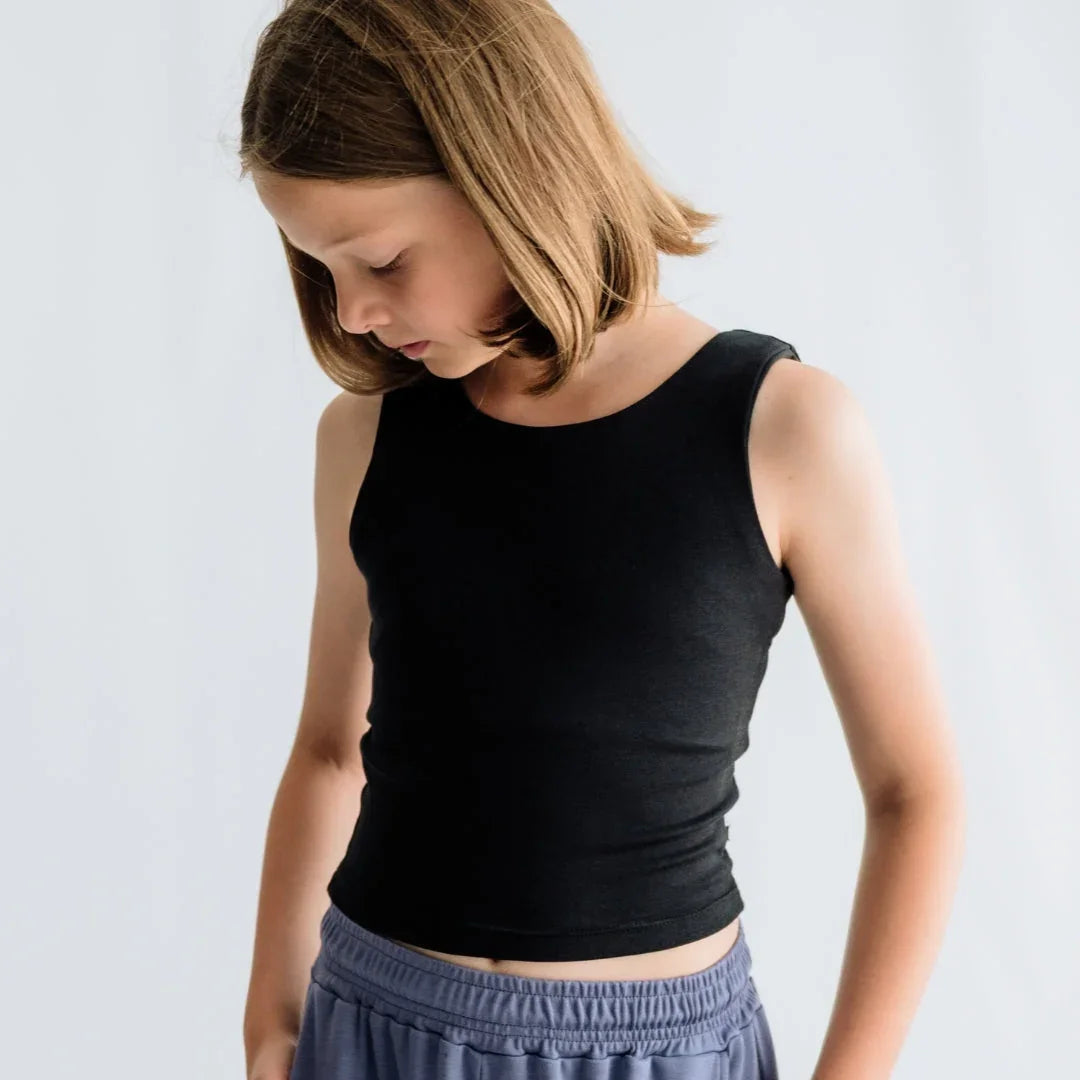 Youth in black tank top and gray shorts against plain white background