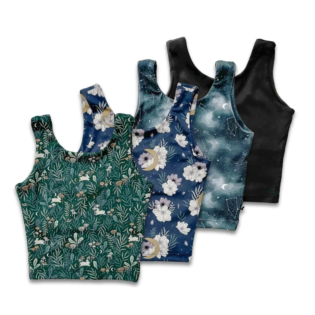 Four cropped tank tops with botanical, floral, celestial, and solid black designs