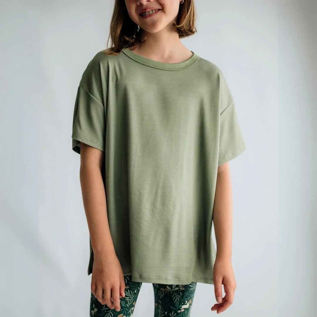 Girl wearing oversized sage green t-shirt and patterned leggings against plain background