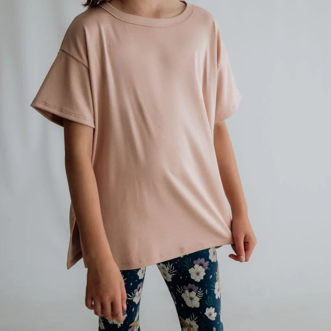 Child wearing oversized blush pink t-shirt and navy floral leggings, neutral background