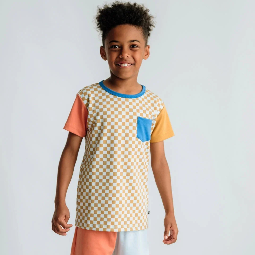 Smiling boy in checkered t-shirt with blue pocket, colorblock sleeves, and shorts
