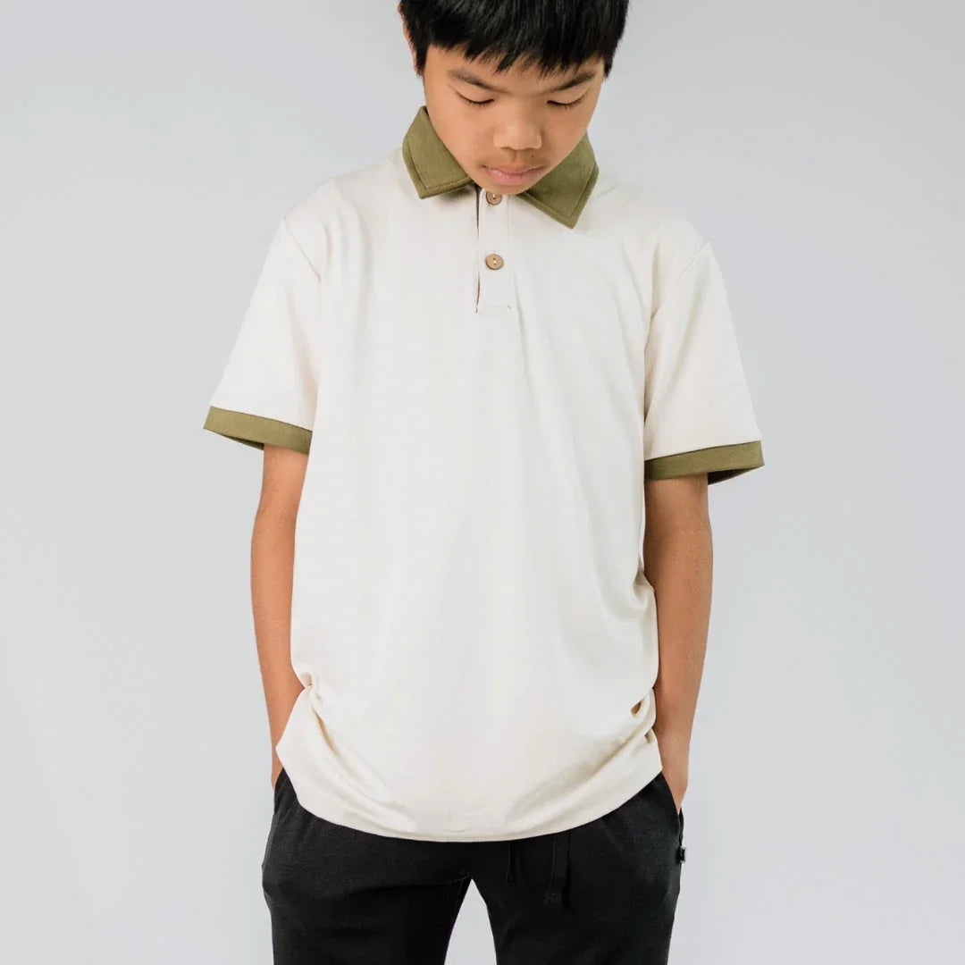 Youth wearing cream polo shirt with olive collar and sleeve trim, casual clothing style