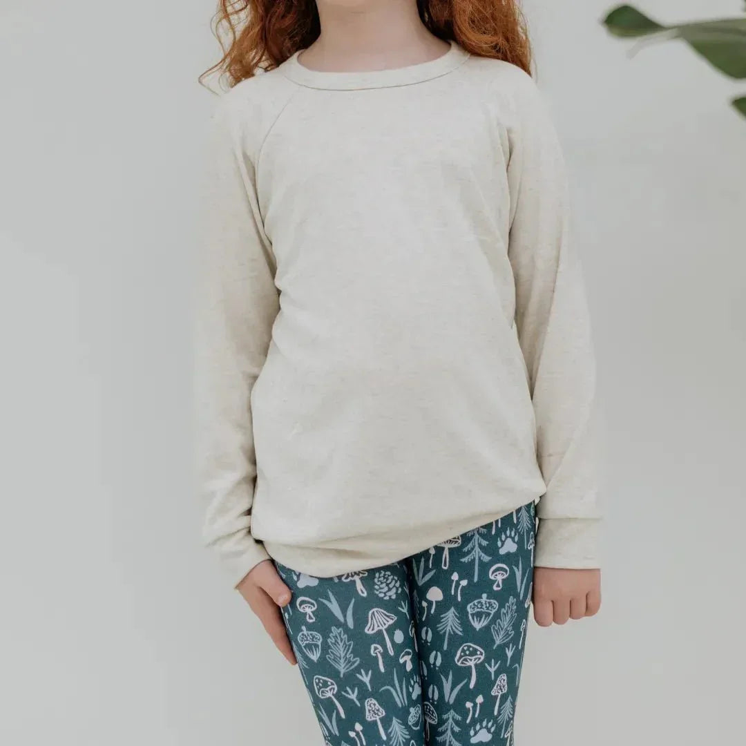 Child wearing cream bamboo raglan pullover and blue patterned leggings