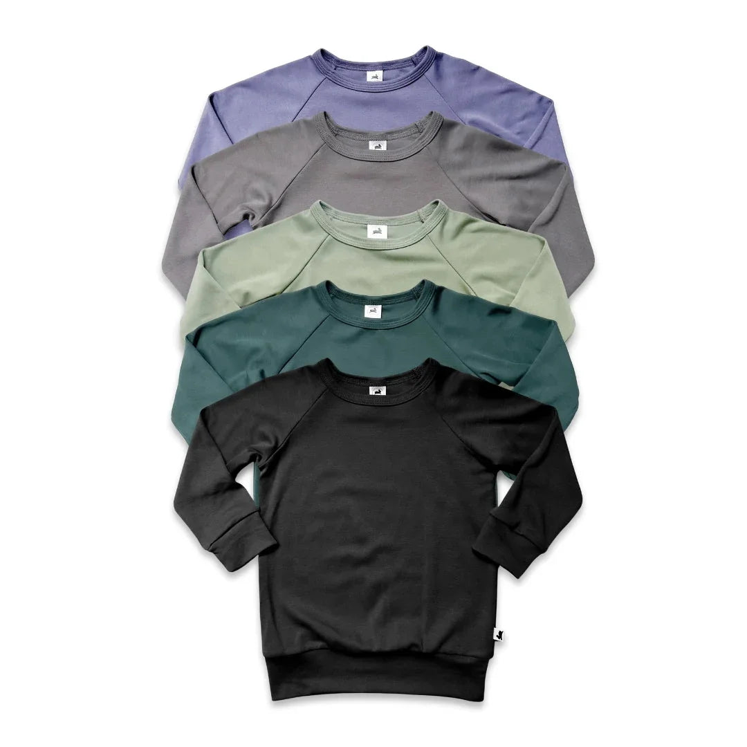 Stacked crewneck sweatshirts in black, teal, sage green, gray, and lavender on white background