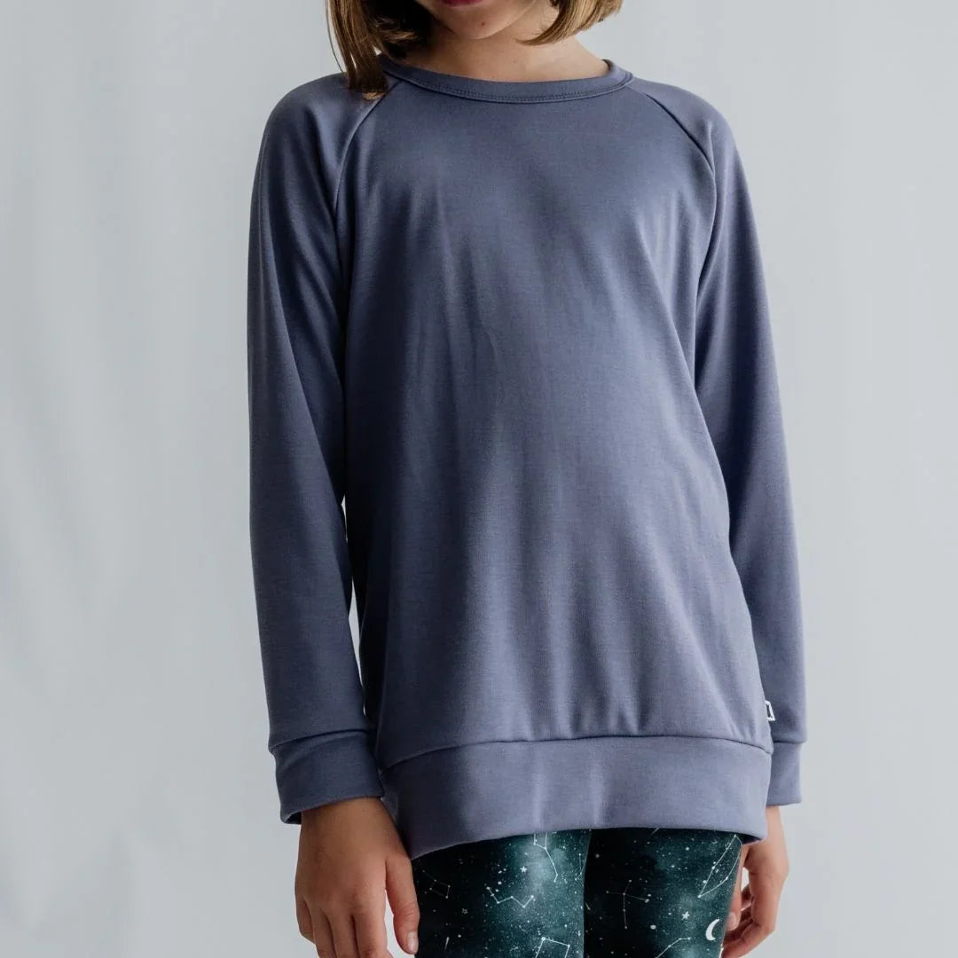 Child wearing a plain gray long sleeve sweatshirt and dark constellation print leggings