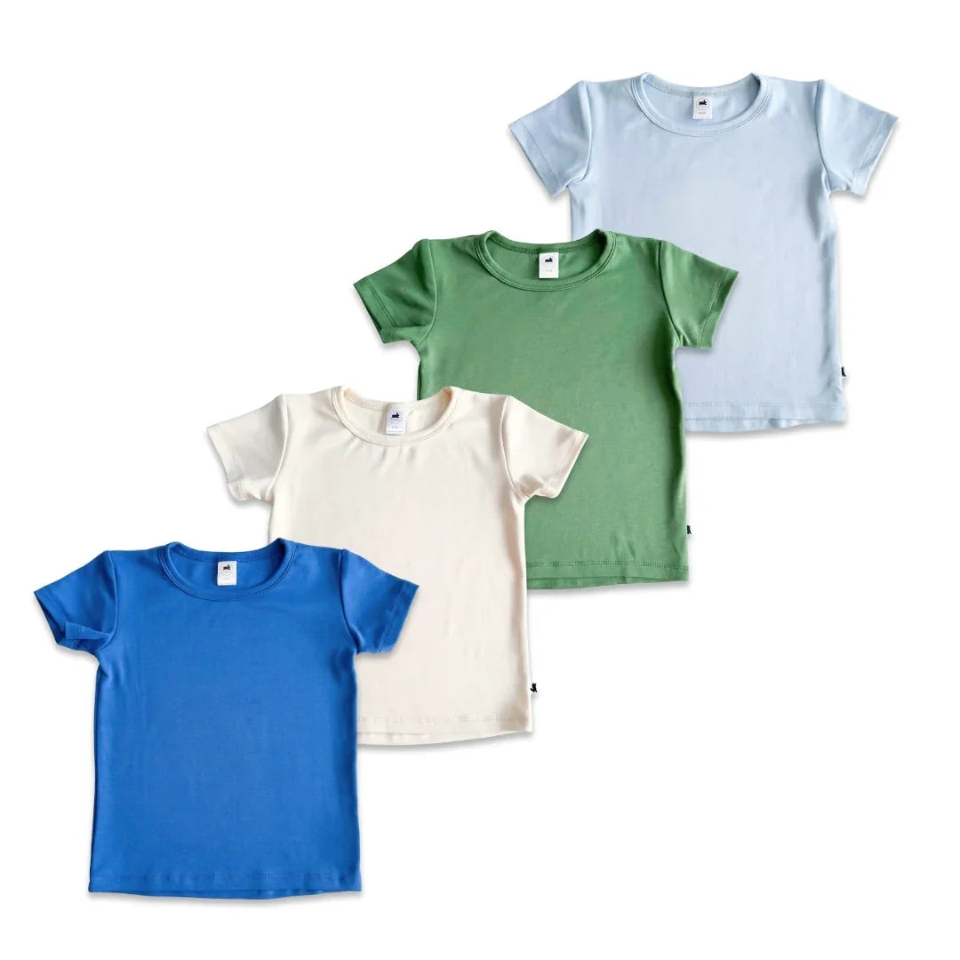 Set of four plain cotton kids t-shirts in blue, cream, green, and light blue on white background.