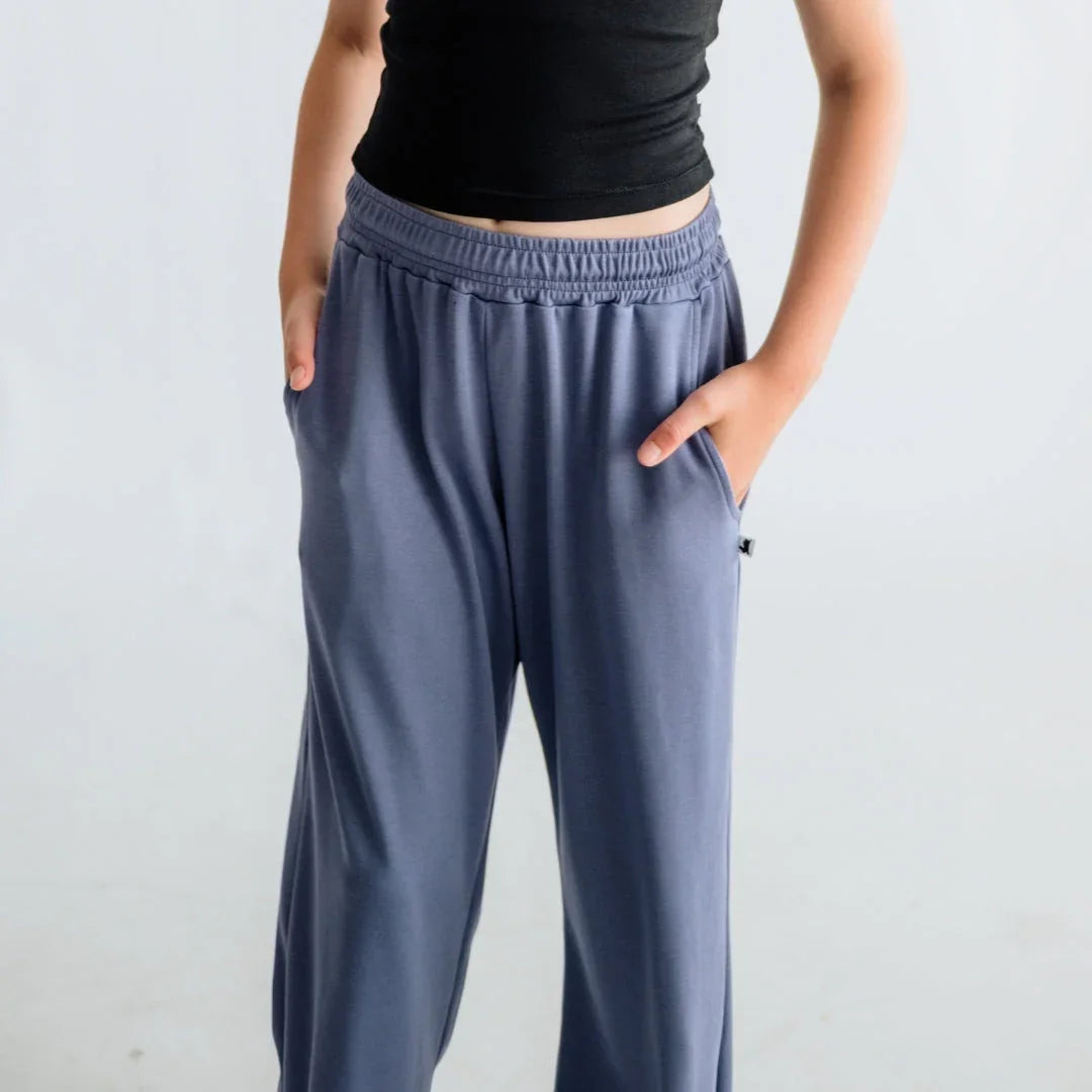 Woman wearing loose blue lounge pants with pockets and a black crop top