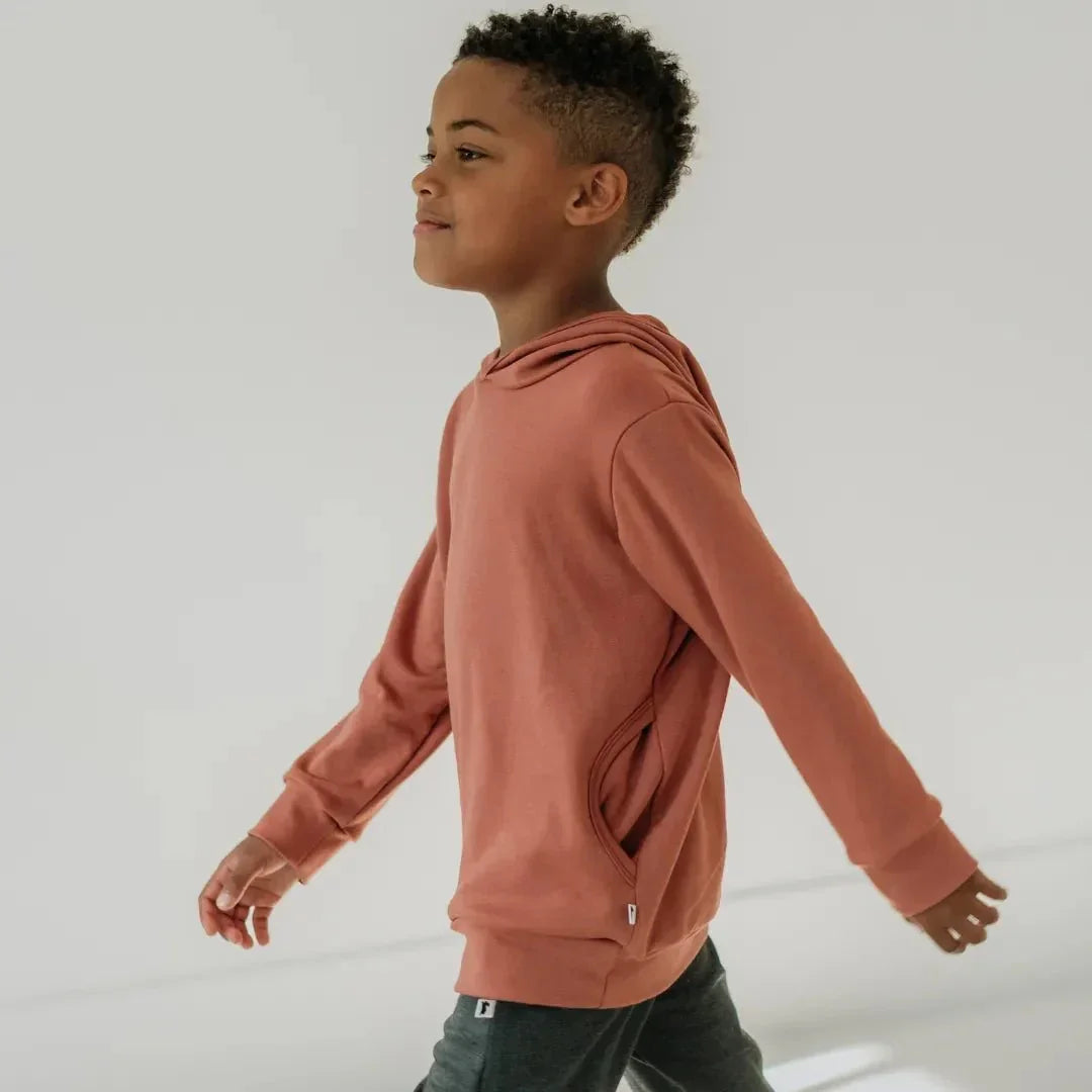 Youth wearing a lightweight bamboo hoodie in dusty rose, walking indoors.