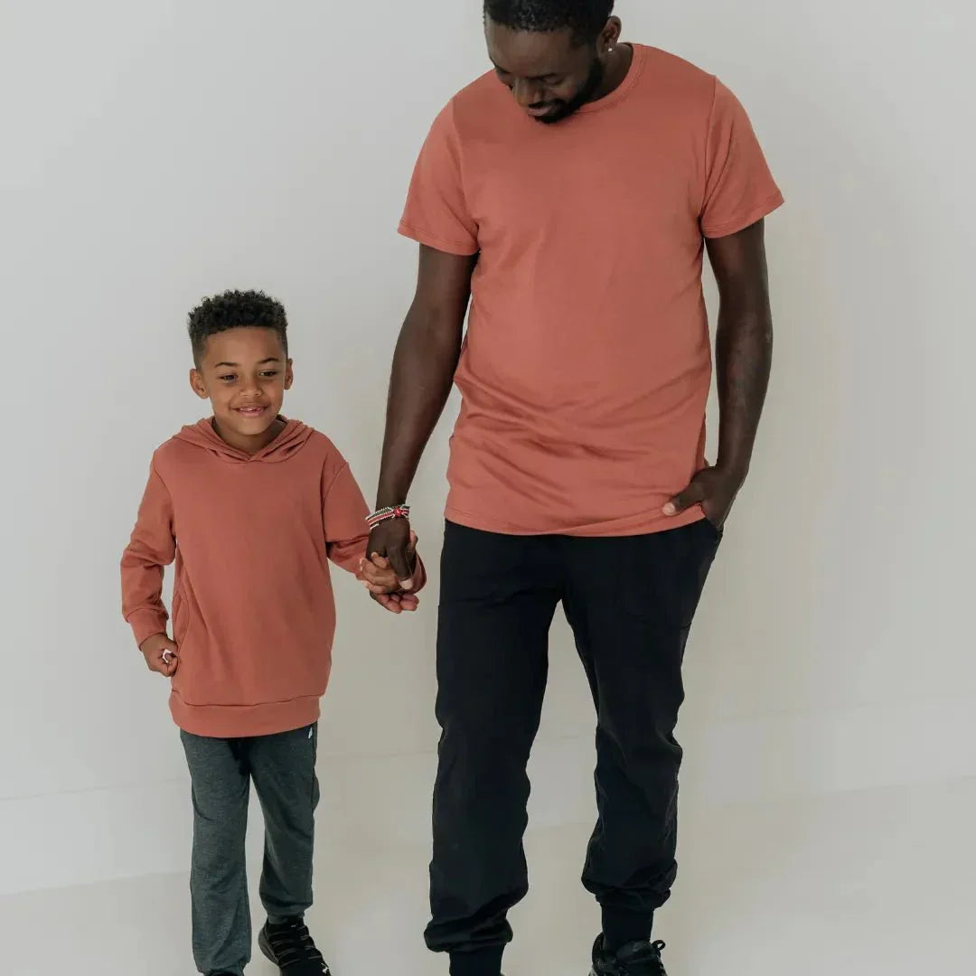 Boy in lightweight bamboo hoodie holding hands with man in matching shirt, white studio