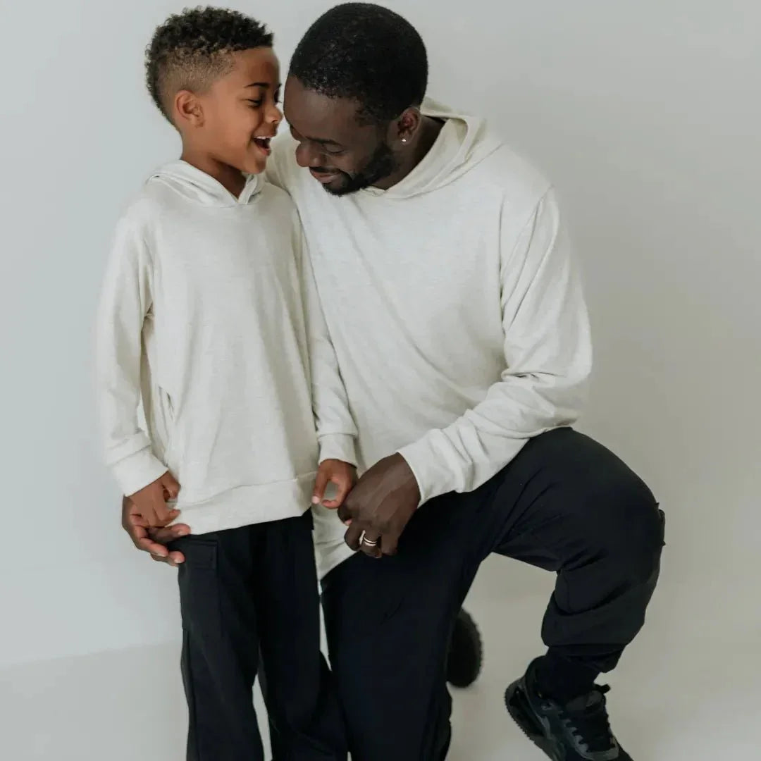 Father and son wearing matching lightweight bamboo hoodies and black pants, smiling together