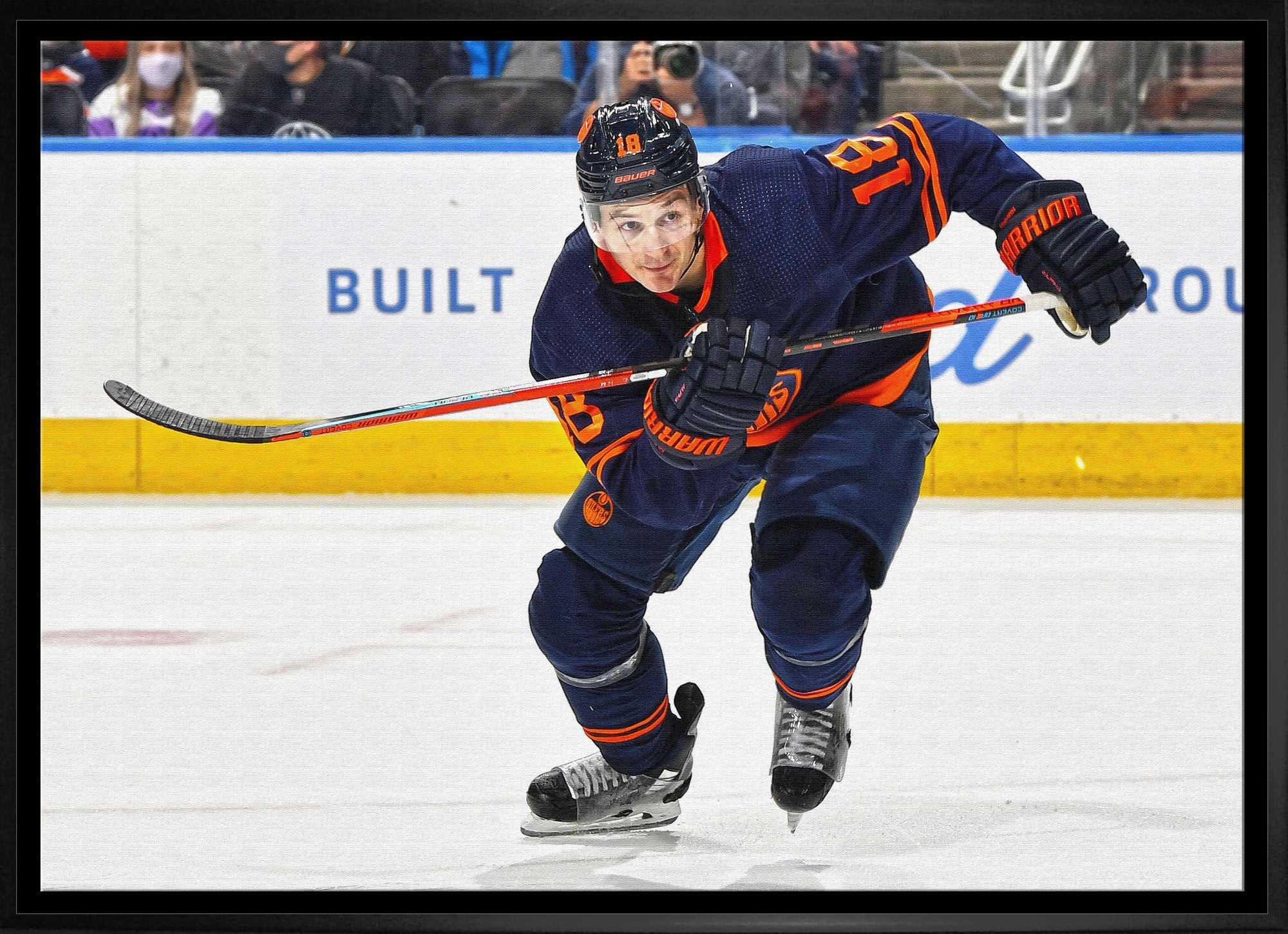 Hockey player in blue and orange jersey skating on ice rink during game
